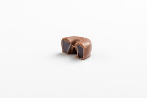 Single Smooth Milk Chocolate Coated Ring cut in half to reveal a chewy aniseed centre