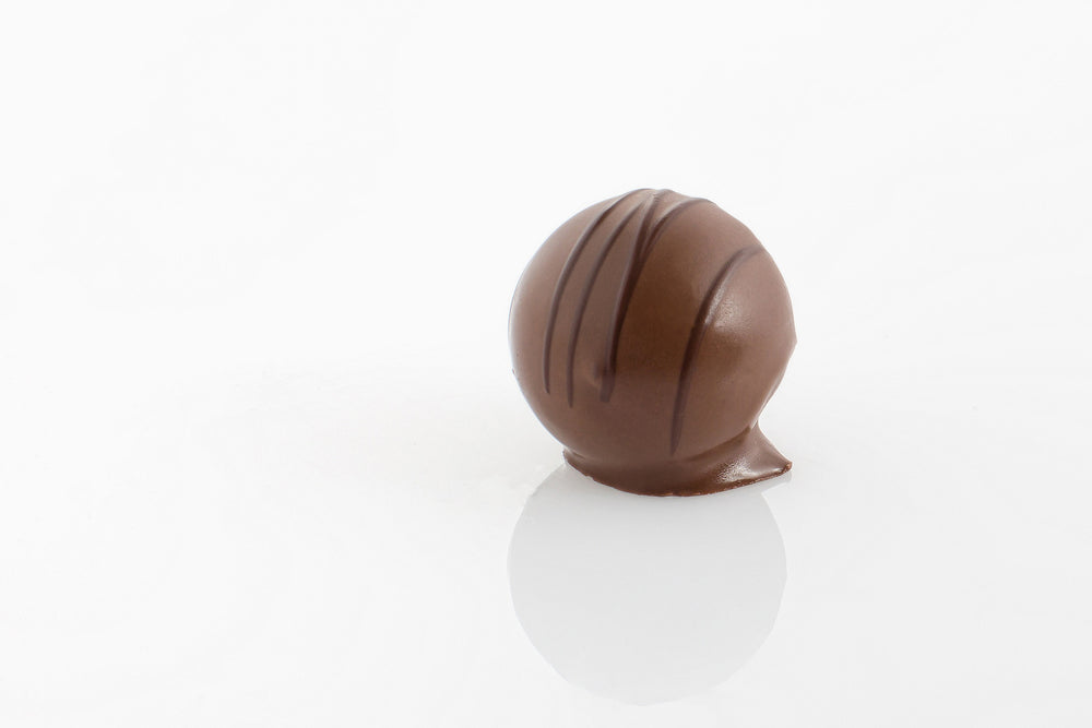 Single Butterscotch Cream Truffle enrobed in couverture milk chocolate with a striped dark chocolate decoration from Share Chocolates