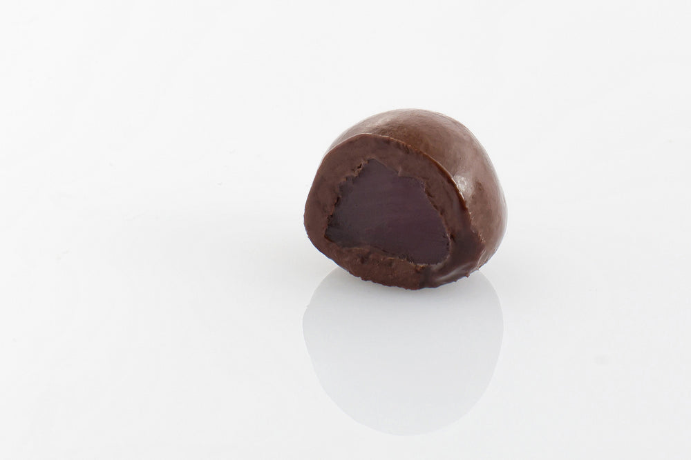 Single Dark Chocolate Coated Raspberry Cut in half to reveal a chewy raspberry centre