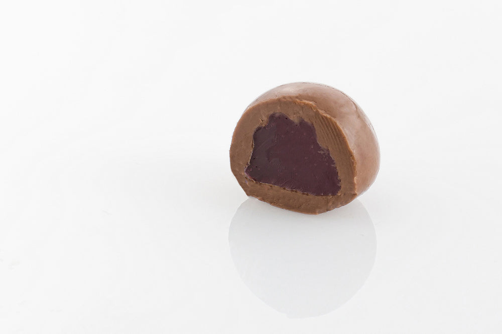 Single Milk Chocolate Coated Raspberry Cut in half to reveal a chewy raspberry centre