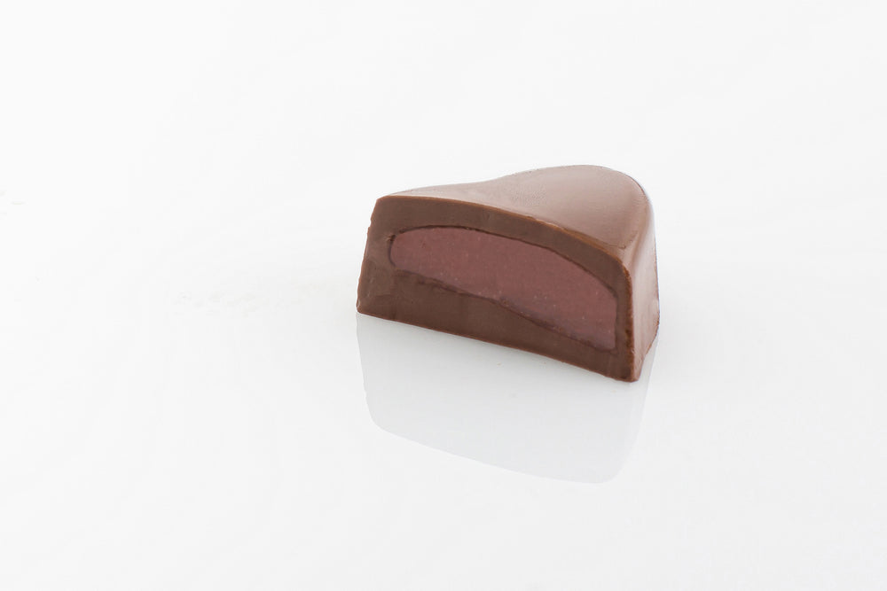 Single Strawberry Cream Truffle Cut in half to reveal a smooth peppermint cream centre