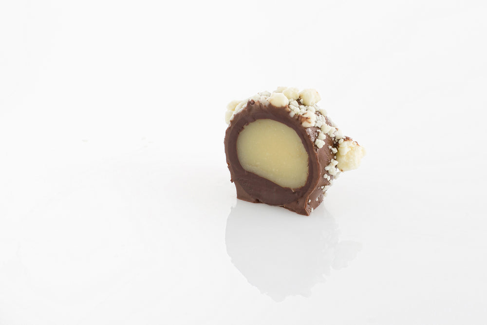 Single Vanilla Ganache Truffle Cut in half to reveal a smooth vanilla and white couverture chocolate truffle centre