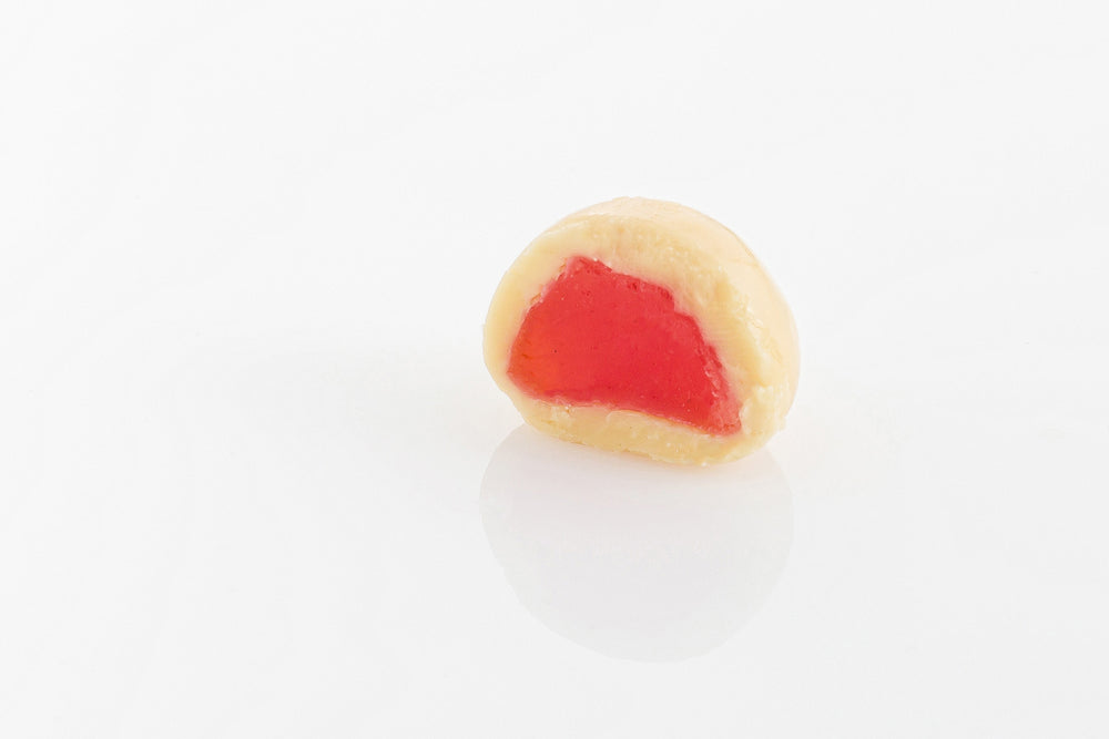 Single White Chocolate Coated Raspberry Cut in half to reveal a chewy raspberry centre